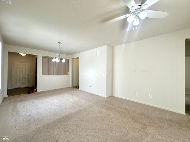 unfurnished room with ceiling fan with notable chandelier, baseboards, and light carpet