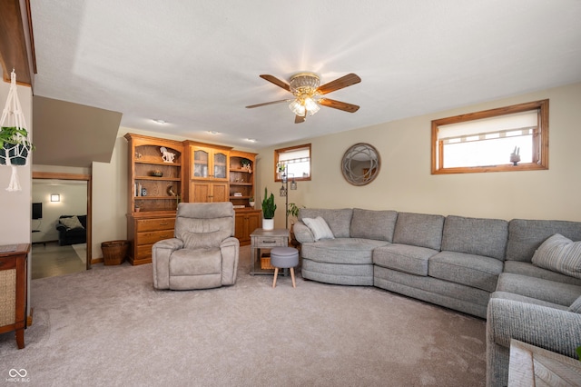 carpeted living area with ceiling fan