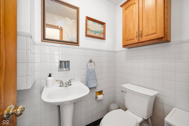 bathroom with tile walls, toilet, and a sink