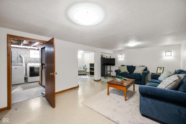 living room with light speckled floor, baseboards, a textured ceiling, and independent washer and dryer