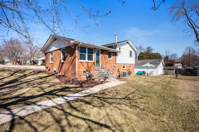 back of house with brick siding, central AC unit, a lawn, and fence