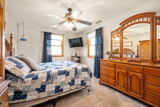 bedroom with visible vents, multiple windows, light colored carpet, and a ceiling fan