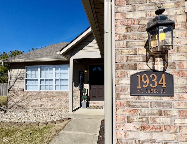 property entrance featuring brick siding and roof with shingles