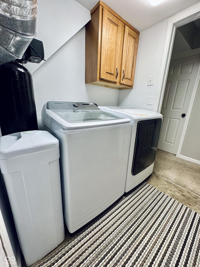 clothes washing area with cabinet space, washing machine and dryer, and baseboards