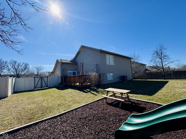 back of house with a wooden deck, a lawn, central AC unit, and a fenced backyard