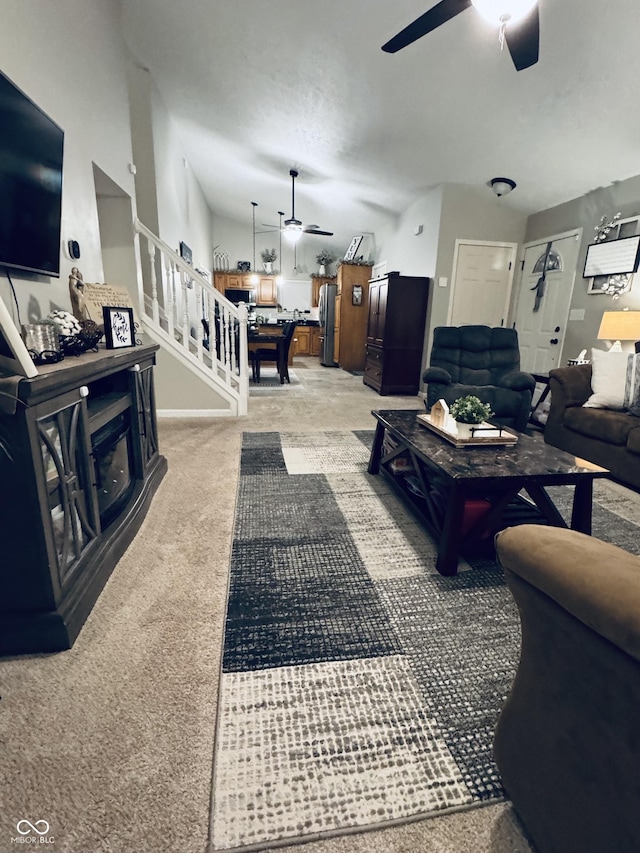 living area featuring stairs, a ceiling fan, and light carpet