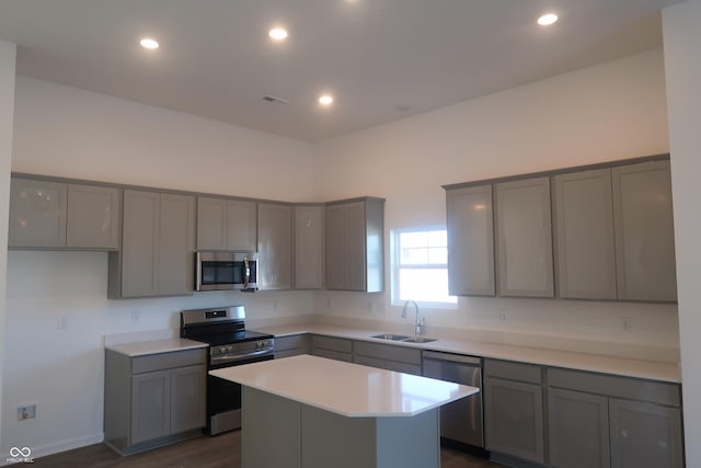 kitchen featuring a kitchen island, light countertops, gray cabinets, appliances with stainless steel finishes, and a sink