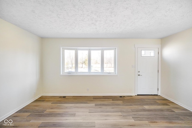 foyer featuring visible vents, wood finished floors, baseboards, and a textured ceiling