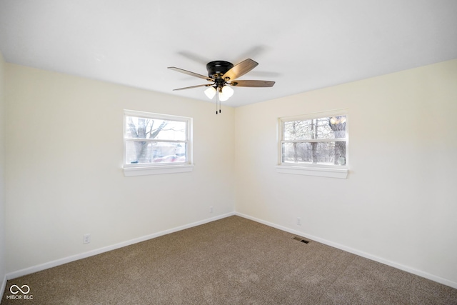 carpeted spare room with baseboards, plenty of natural light, visible vents, and ceiling fan