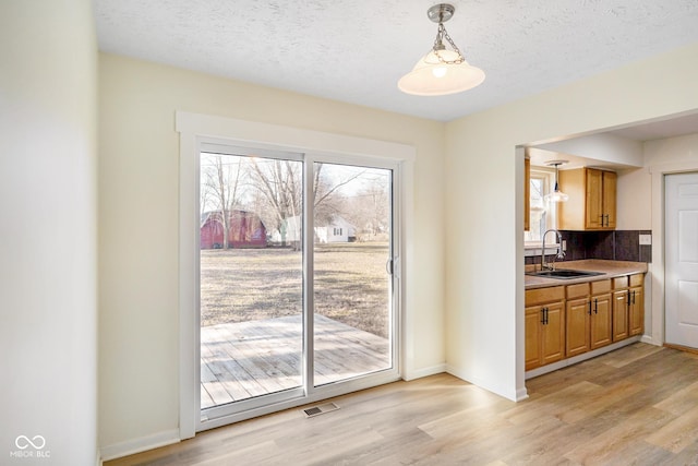 dining space featuring visible vents, baseboards, light wood-style floors, and a textured ceiling