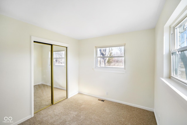 unfurnished bedroom with visible vents, multiple windows, baseboards, and carpet floors