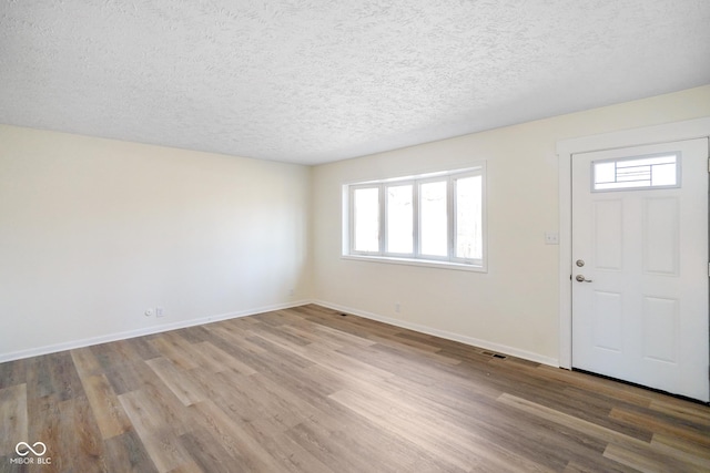 foyer entrance featuring plenty of natural light, wood finished floors, baseboards, and a textured ceiling