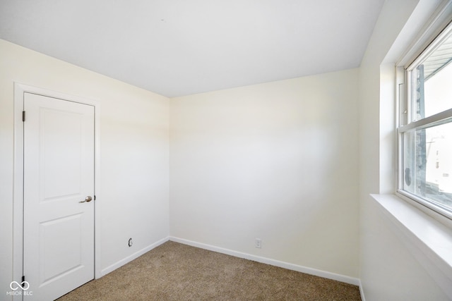 unfurnished room with baseboards and carpet