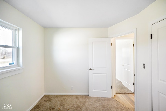 unfurnished bedroom featuring baseboards and light colored carpet