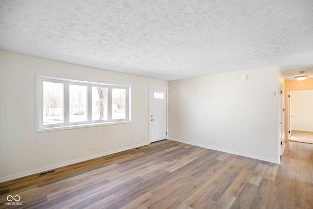 entrance foyer with visible vents, baseboards, a textured ceiling, and wood finished floors