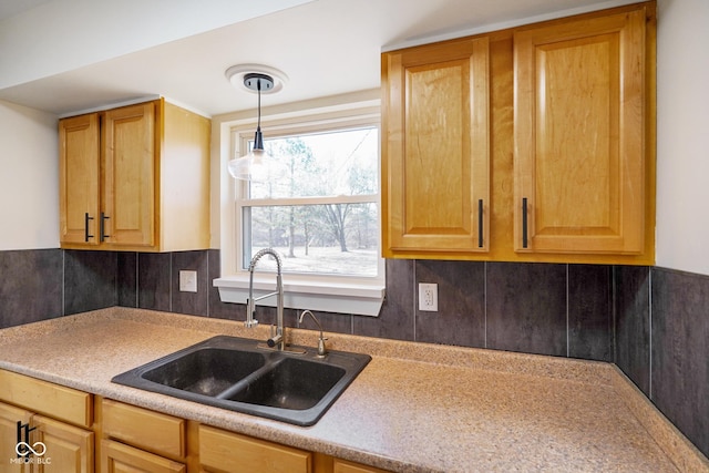 kitchen with decorative light fixtures, decorative backsplash, light countertops, and a sink