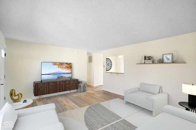 living room with wood finished floors, visible vents, and a textured ceiling