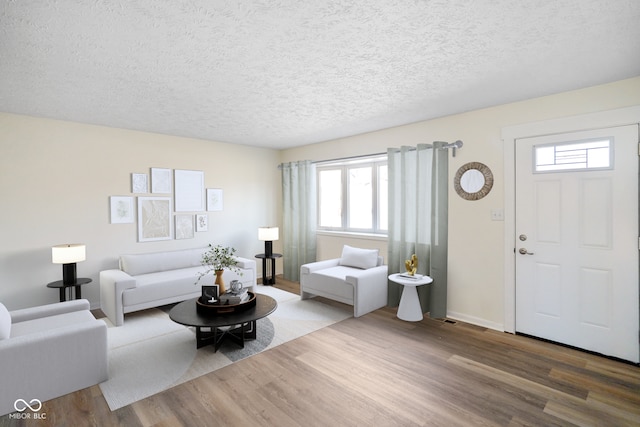 living room with baseboards, a textured ceiling, and wood finished floors