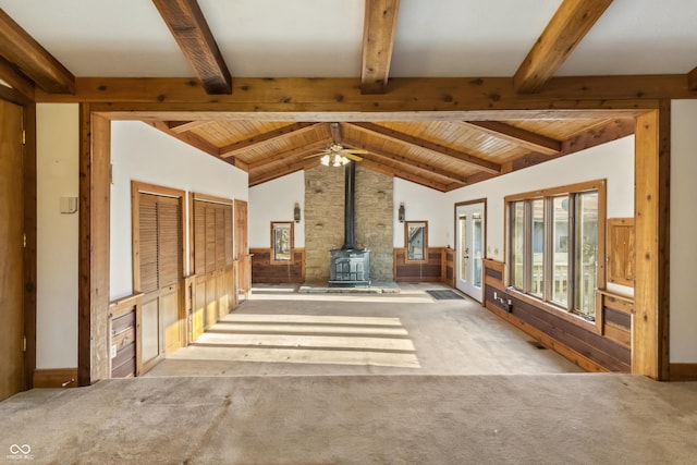 unfurnished living room with lofted ceiling with beams, carpet, wood ceiling, and a wood stove