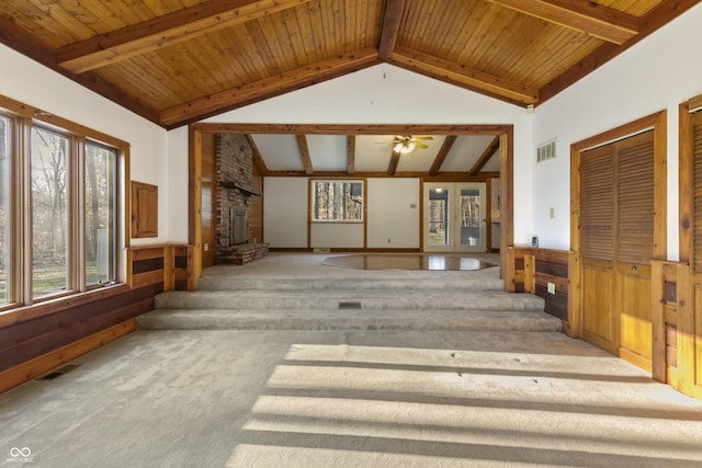 unfurnished living room featuring visible vents, a large fireplace, lofted ceiling with beams, carpet flooring, and wainscoting