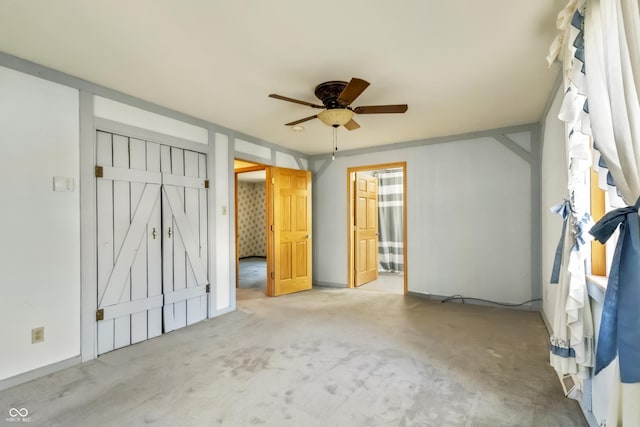 unfurnished bedroom featuring ceiling fan, ensuite bath, and carpet