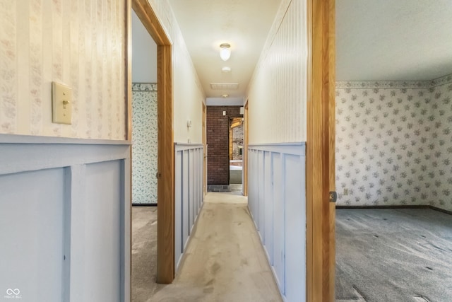 corridor with wallpapered walls, carpet, visible vents, and wainscoting