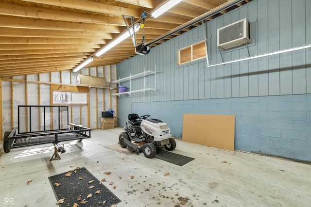 garage with a wall unit AC, concrete block wall, and a garage door opener