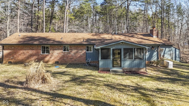 back of house with brick siding, a lawn, a chimney, a sunroom, and crawl space