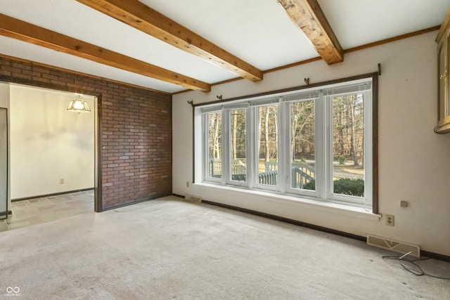 carpeted spare room featuring plenty of natural light, beamed ceiling, baseboards, and visible vents