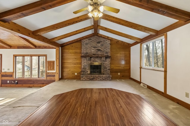 unfurnished living room featuring plenty of natural light, wooden walls, and a fireplace