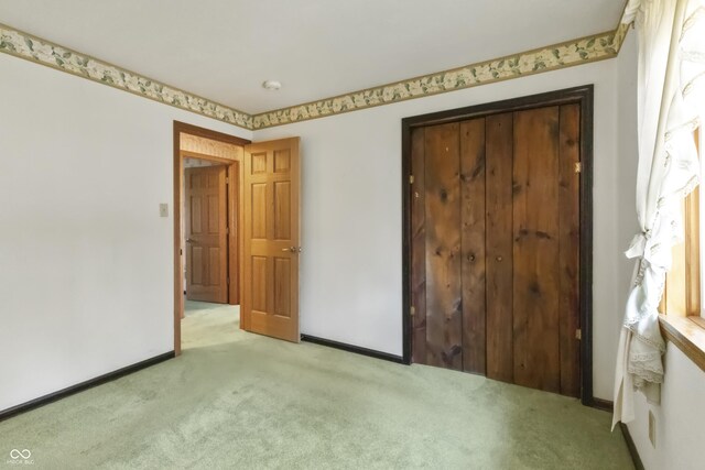 unfurnished bedroom with baseboards, light carpet, and a closet