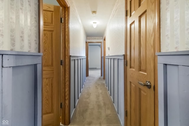 corridor featuring light colored carpet and wallpapered walls