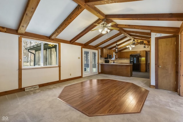 unfurnished living room with visible vents, baseboards, vaulted ceiling with beams, ceiling fan, and light colored carpet