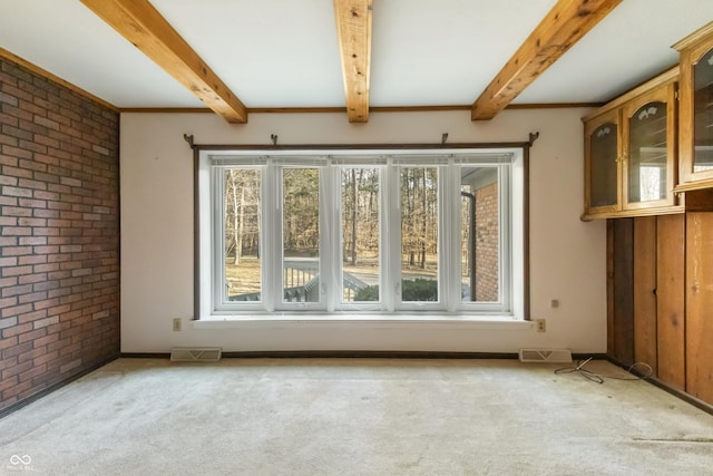 carpeted spare room featuring visible vents, a healthy amount of sunlight, beamed ceiling, and brick wall