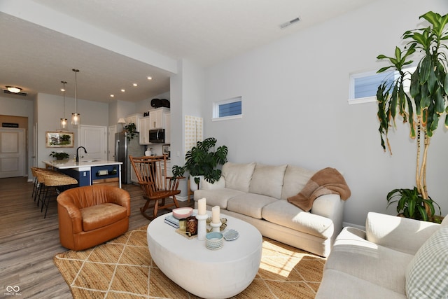 living area with recessed lighting, visible vents, and light wood finished floors