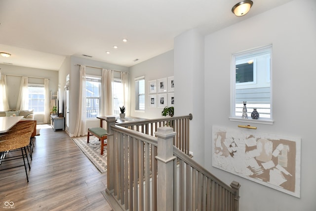 hallway with an upstairs landing, recessed lighting, and wood finished floors