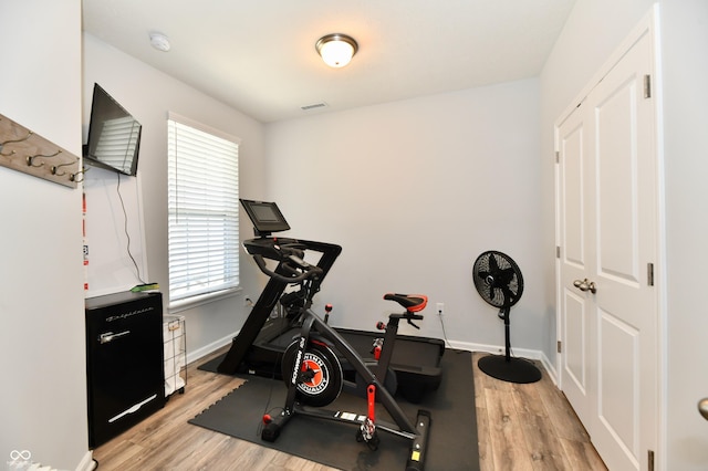 exercise room featuring visible vents, baseboards, and light wood finished floors