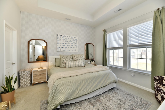 bedroom featuring wallpapered walls, a tray ceiling, and visible vents