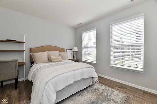 bedroom with visible vents, baseboards, and wood finished floors