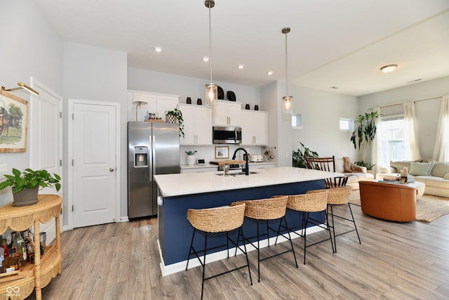 kitchen featuring a breakfast bar, light countertops, appliances with stainless steel finishes, light wood-style floors, and white cabinetry