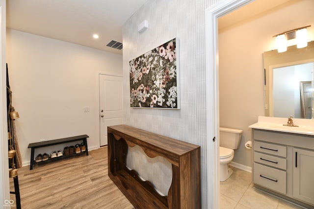 bathroom with vanity, baseboards, visible vents, tile patterned floors, and toilet