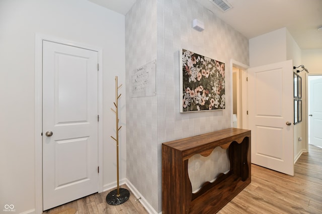 hallway with light wood-type flooring, baseboards, and visible vents