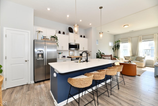 kitchen with a sink, a kitchen breakfast bar, light wood finished floors, and stainless steel appliances