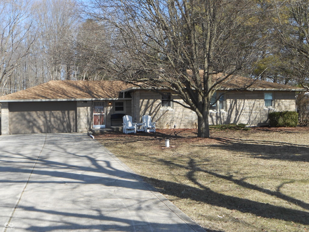 view of front of property with a garage, a front yard, roof with shingles, and driveway