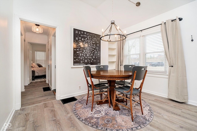 dining area featuring a chandelier, light wood-type flooring, baseboards, and vaulted ceiling