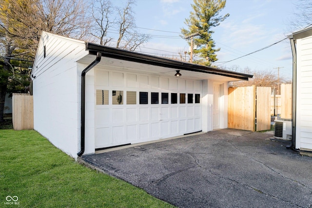 detached garage featuring cooling unit and fence