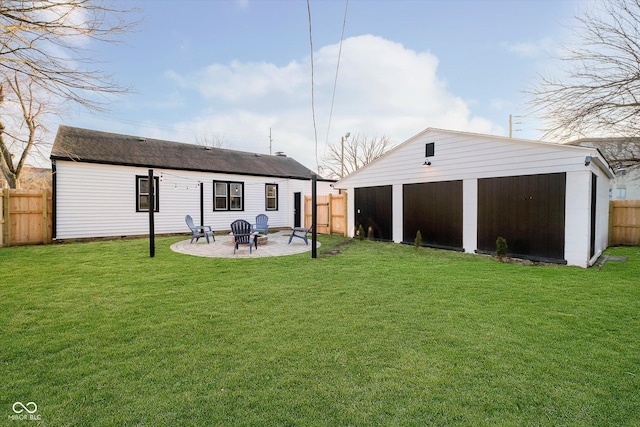 rear view of property featuring an outdoor fire pit, a lawn, a fenced backyard, an outbuilding, and a patio