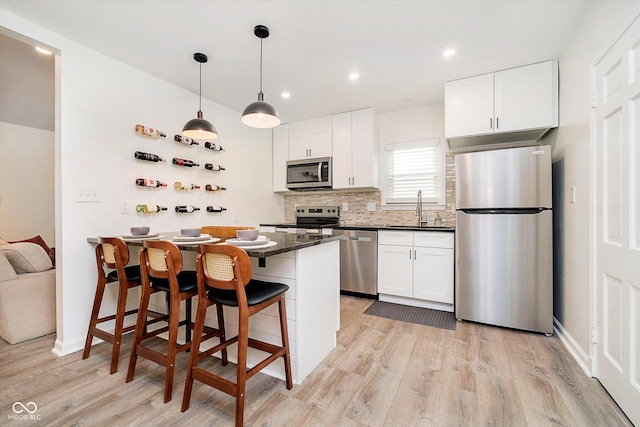 kitchen featuring dark countertops, tasteful backsplash, appliances with stainless steel finishes, a kitchen breakfast bar, and a sink