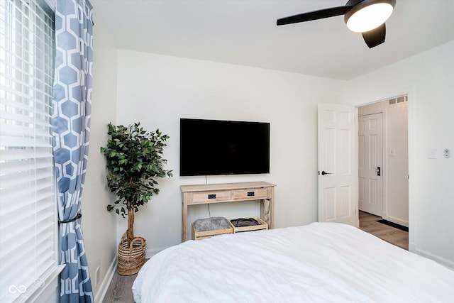 bedroom with visible vents, baseboards, wood finished floors, and a ceiling fan