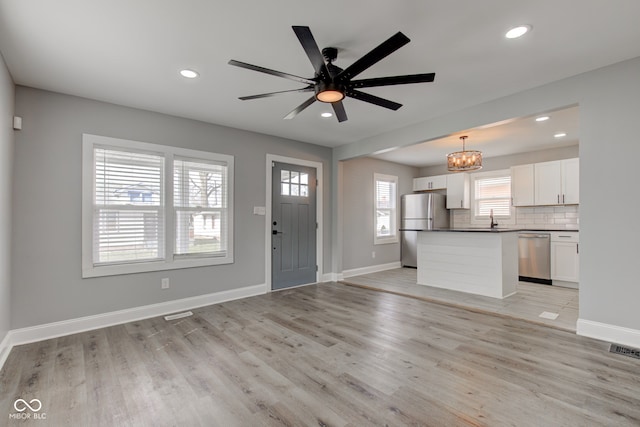 301 Villa Ave, Indianapolis, IN 46201 - interior space featuring ceiling fan with notable chandelier, a kitchen island, backsplash, stainless steel appliances, and light wood-style floors